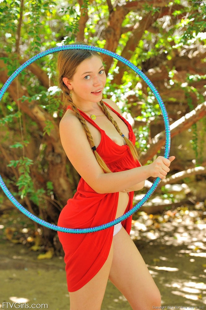 Young cute teen in pigtails plays hula hoop naked on the front lawn  